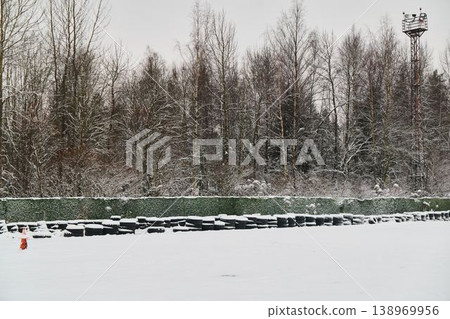 Overcast winter landscape featuring barriers and tranquil forest backdrop Overcast winter landscape featuring barriers and tranquil forest backdrop 138969956
