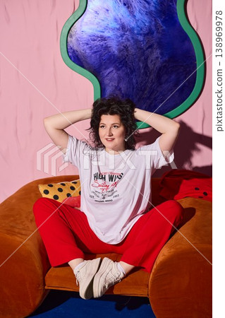 Woman sitting comfortably amidst bold colored decor and playful atmosphere Woman sitting comfortably amidst bold colored decor and playful atmosphere 138969978