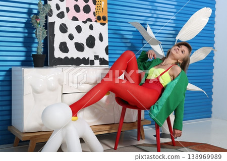 Contemporary woman strikes artistic pose with vivid attire and props 138969989