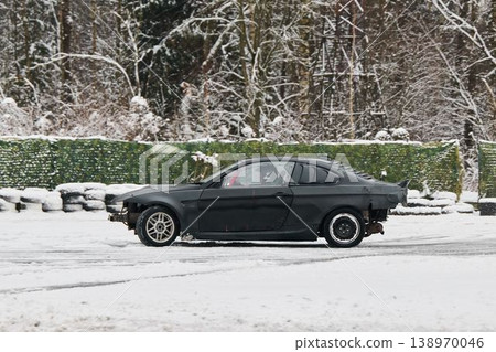 Quiet snowy street scene with stylish automobile and tire stack 138970046