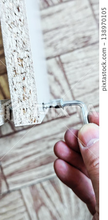 Tightening a screw in furniture assembled from flat parts manually using an Allen key. 138970105