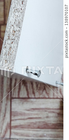 Close up of screwing a cam lock screw into a flat pack furniture panel. Close up of screwing a cam lock screw into a flat pack furniture panel. 138970107