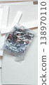 A plastic bag containing furniture hinges and screws, disassembled for assembly. 138970110