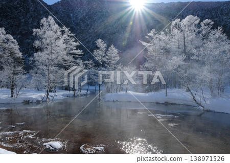 晨曦中,覆蓋著霜雪的樹林閃閃發光,水面上升騰起陣陣水霧-宛如一輪奇幻的冬日池塘,沐浴在陽光之中。 晨曦中,覆蓋著霜雪的樹林閃閃發光,水面上升騰起陣陣水霧-宛如一輪奇幻的冬日池塘,沐浴在陽光之中。 138971526