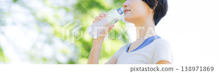 一位女性在戶外綠意盎然的環境中補充水分的側面肖像;她可能正在散步、跑步或其他運動;沒有臉部特徵。 一位女性在戶外綠意盎然的環境中補充水分的側面肖像;她可能正在散步、跑步或其他運動;沒有臉部特徵。 138971869