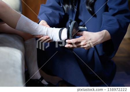 A Japanese mother's hands as she puts shoes on her child. 138972222