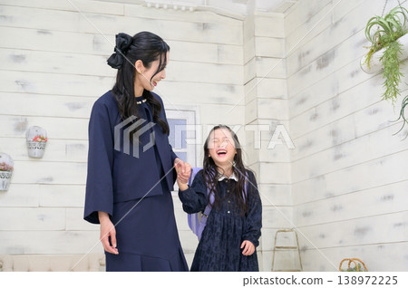 A smiling Japanese girl holding her mother's hand. 138972225