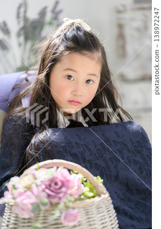 A Japanese girl with a schoolbag on her back, holding a basket of flowers in front of her. 138972247