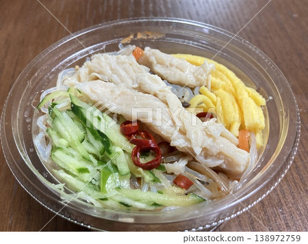 Side dishes in a clear container: glass noodle salad with cucumber, shredded egg, and steamed chicken. 138972759