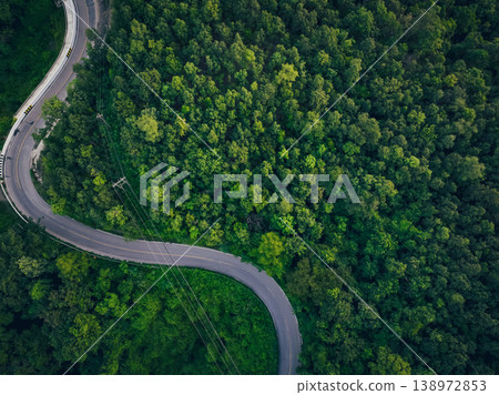 Aerial view of dense green trees in forest capture CO2 and curve highway road. Green trees background for carbon neutrality and net zero emissions concept. Sustainable green environment. Carbon credit Aerial view of dense green trees in forest capture CO2 and curve highway road. Green trees background for carbon neutrality and net zero emissions concept. Sustainable green environment. Carbon credit 138972853