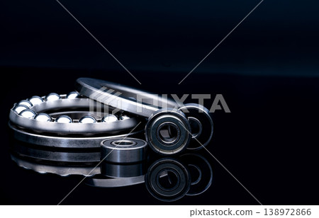 Stainless steel thrust ball bearing. Set of thrust ball bearing and shiny silver ball bearing. Spare parts for roller machine in heavy machinery and automotive industry. Round metal wheel. 138972866