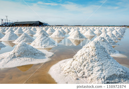 Sea salt farm and barn in Thailand. Organic sea salt. Raw material of salt industrial. Sodium Chloride. Solar evaporation system. Iodine source. Worker working in farm on sunny day with blue sky. Sea salt farm and barn in Thailand. Organic sea salt. Raw material of salt industrial. Sodium Chloride. Solar evaporation system. Iodine source. Worker working in farm on sunny day with blue sky. 138972874