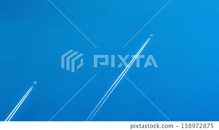 Airplane with white condensation tracks. Jet plane on clear blue sky with vapor trail. Travel by airplane concept. Trails of exhaust gas from airplane engine. Aircraft with white stripes. Airplane with white condensation tracks. Jet plane on clear blue sky with vapor trail. Travel by airplane concept. Trails of exhaust gas from airplane engine. Aircraft with white stripes. 138972875