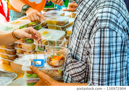 Volunteers giving food to poor people in urban community, charity and humanitarian aid concept. Private enterprise support, meal distribution for underprivileged groups and social responsibility. Volunteers giving food to poor people in urban community, charity and humanitarian aid concept. Private enterprise support, meal distribution for underprivileged groups and social responsibility. 138972904