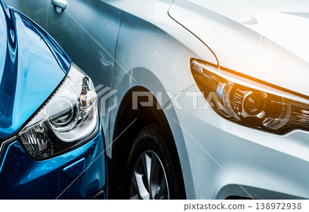 Close up headlamp light of blue and white SUV car. Blue car parked beside white car. Automotive industry concept. Electric or hybrid auto concept. Car service. Road trip adventure. Automobile rental. 138972938