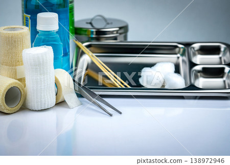Wound care dressing set with stainless steel plate forceps iodine cup and bandage, medical supply. Antiseptic saline bottles and instruments for treatment and infection prevention in healthcare. Wound care dressing set with stainless steel plate forceps iodine cup and bandage, medical supply. Antiseptic saline bottles and instruments for treatment and infection prevention in healthcare. 138972946