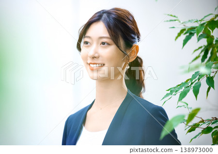 一位年輕的日本女商人面帶微笑地站在燈火通明的辦公室裡。 138973000