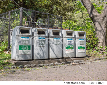 Sorting bins and multilingual signs installed in a park surrounded by trees Sorting bins and multilingual signs installed in a park surrounded by trees 138973025