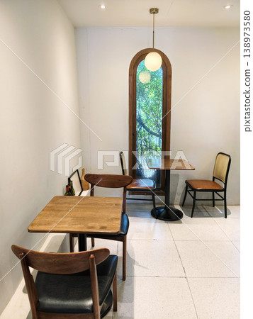 Cafe interior of wood table and chairs by window in tropical tree Cafe interior of wood table and chairs by window in tropical tree 138973580