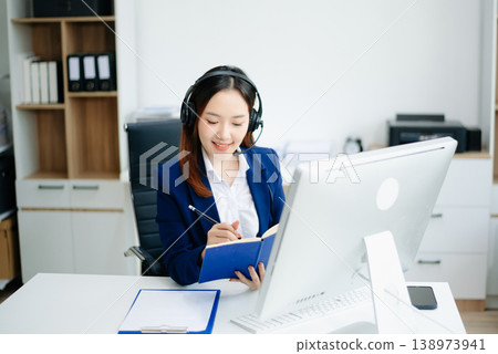 Serious call center operator in wireless headset talking with customer, woman in headphones with microphone consulting client Serious call center operator in wireless headset talking with customer, woman in headphones with microphone consulting client 138973941