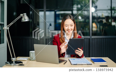 Confident businesswomen working on finance analysis with a tablet and laptop at office desk. Perfect for business, accounting Confident businesswomen working on finance analysis with a tablet and laptop at office desk. Perfect for business, accounting 138973942