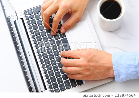 Image of a man drinking coffee and working on a laptop Image of a man drinking coffee and working on a laptop 138974564