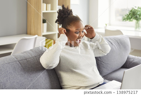 Happy excited African American woman communicating with friend via video call on laptop 138975217