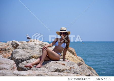 Woman relaxing on seaside rocks in bikini during summer vacation 138976400
