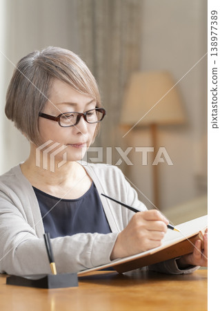 Senior woman writing an end-of-life note in the living room Senior woman writing an end-of-life note in the living room 138977389