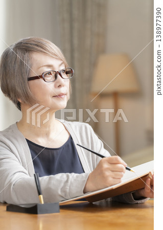 Senior woman writing an end-of-life note in the living room Senior woman writing an end-of-life note in the living room 138977390