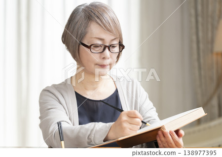 Senior woman writing an end-of-life note in the living room Senior woman writing an end-of-life note in the living room 138977395