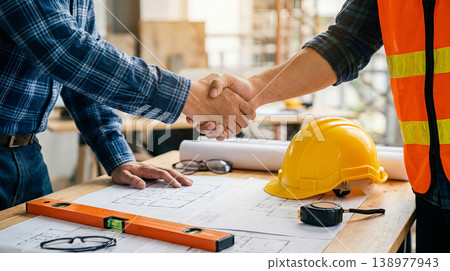 Architect and Construction Engineer Shaking Hands over Project Blueprints at Site 138977943