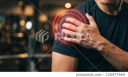 Man holding his shoulder in pain during gym workout with red injury highlight 138977944