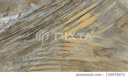 Aerial top view tire track on dirt sand mud, Texture of wet mud road with puddle and Tyre or tire track in countryside, Wheel tyre or tire track on mud, texture and background. Aerial top view tire track on dirt sand mud, Texture of wet mud road with puddle and Tyre or tire track in countryside, Wheel tyre or tire track on mud, texture and background. 138978072