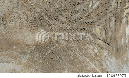 Aerial top view tire track on dirt sand mud, Texture of wet mud road with puddle and Tyre or tire track in countryside, Wheel tyre or tire track on mud, texture and background. Aerial top view tire track on dirt sand mud, Texture of wet mud road with puddle and Tyre or tire track in countryside, Wheel tyre or tire track on mud, texture and background. 138978075