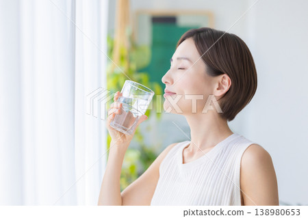 美麗的畫面：一位女子在窗邊喝水。 138980653