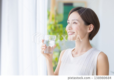 美麗的畫面:一位女子在窗邊喝水。 美麗的畫面:一位女子在窗邊喝水。 138980684