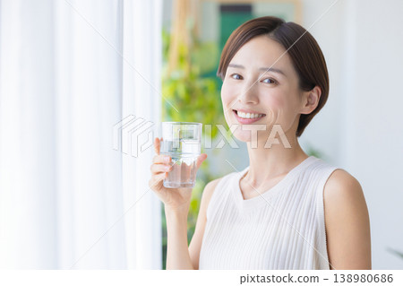 美麗的畫面：一位女子在窗邊喝水。 138980686