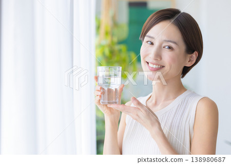 美麗的畫面:一位女子在窗邊喝水。 美麗的畫面:一位女子在窗邊喝水。 138980687