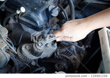 Hand of mechanic using a silver combination wrench to work on a pulley bolt Hand of mechanic using a silver combination wrench to work on a pulley bolt 138981108