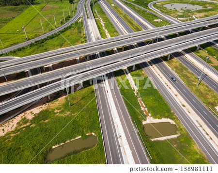 Drone shot a large highway interchange crossing over green farmlands in Thailand 138981111