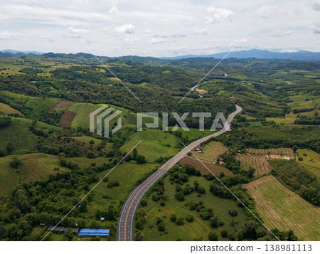 Aerial drone view of Highway winding through lush green mountains between Nan, Thailand. A scenic landscape of the road surrounded by tropical forest and a peaceful countryside 138981113
