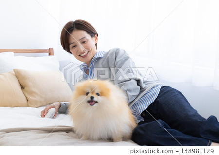 Lifestyle: A woman and a Pomeranian relaxing in bed 138981129
