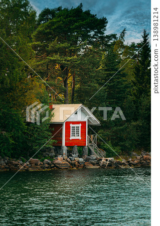Traditional Red Cabin on a Rocky Shoreline Traditional Red Cabin on a Rocky Shoreline 138981214