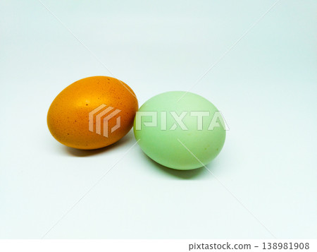 Two whole raw eggs, one speckled brown and one smooth pale green, resting on a white background, suitable for organic food and farming themes 138981908