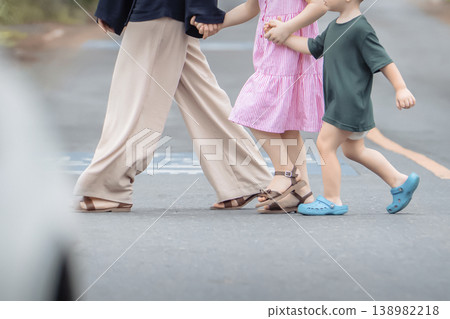 The concept is road safety, and the rules of crossing the road with children in the right place, the rules of the road and pedestrians. A family - a mother with young children holding hands crossing The concept is road safety, and the rules of crossing the road with children in the right place, the rules of the road and pedestrians. A family - a mother with young children holding hands crossing 138982218