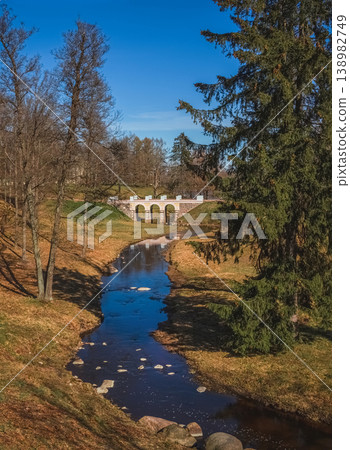 Stone bridge arches gracefully over a quiet stream, vertical view 138982749