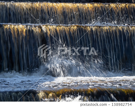 Water cascades down stone steps in golden sunlight Water cascades down stone steps in golden sunlight 138982754