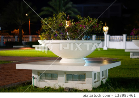 Decorative White Planter in Illuminated Urban Park at Night with Serene Ambiance. 138983461