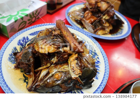 餐桌上擺放著盛在藍色日式盤子裡的燉魚。 餐桌上擺放著盛在藍色日式盤子裡的燉魚。 138984177